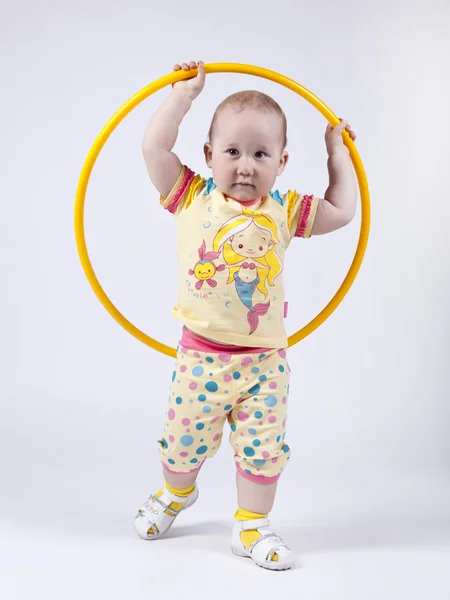 Uma menina em um vestido amarelo posando em estúdio com um hula hoo — Fotografia de Stock