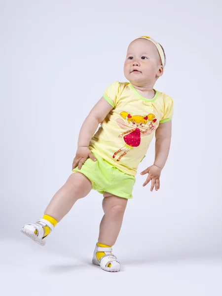 En liten flicka i en gul klänning som poserar i studio — Stockfoto