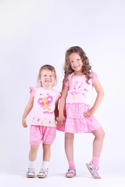 Two little girls in pink dresses holding hands — Stock Photo, Image