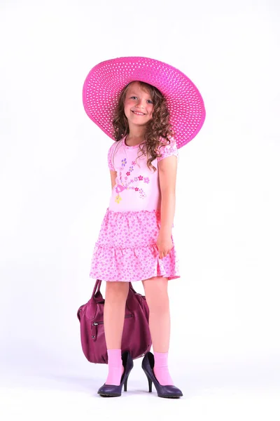 Klein meisje in een mooie roze jurk met hoed en tas — Stockfoto