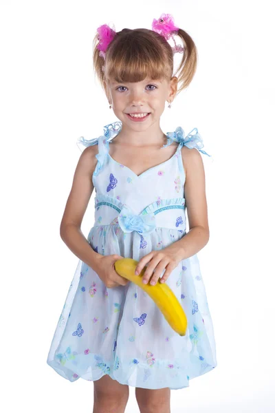 Pretty girl in a blue dress with a banana in her hands — Stock Photo, Image