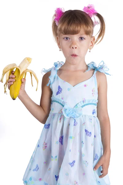 Mooi meisje in een blauwe jurk met een banaan in haar handen — Stockfoto