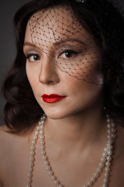 Mature woman in pearl necklace and a black veil