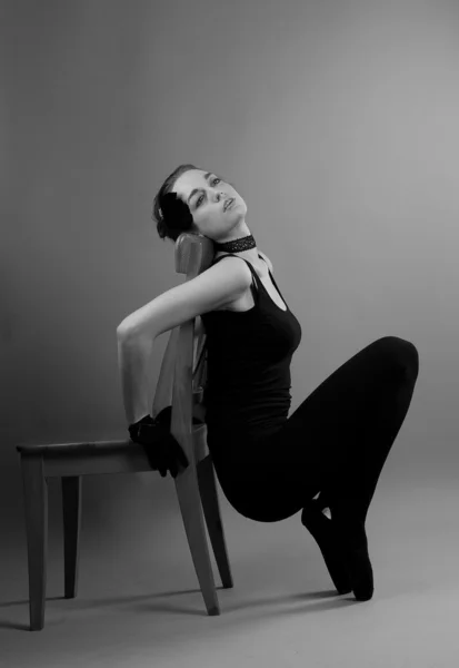 Joven bailarina realiza ejercicios cerca de la silla —  Fotos de Stock