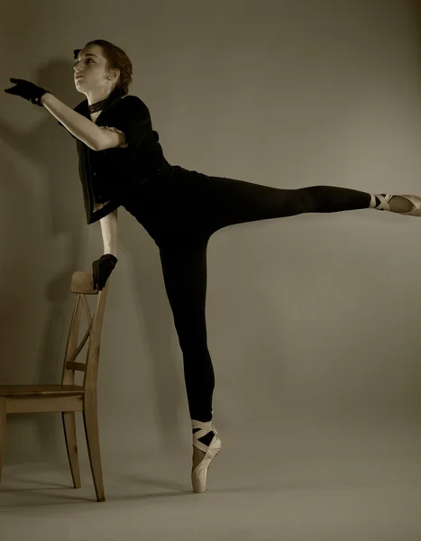 Jonge ballerina voert oefeningen in de buurt van de stoel — Stockfoto