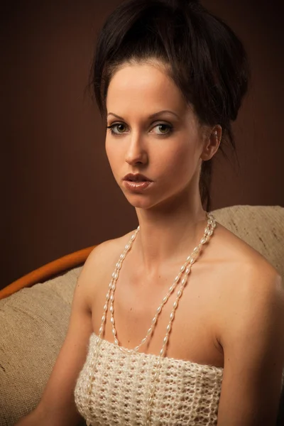A brunette woman in white dress sitting in a white chair — Stock Photo, Image