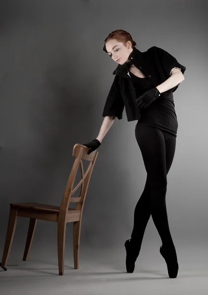 Jovem bailarina realiza exercícios perto da cadeira — Fotografia de Stock