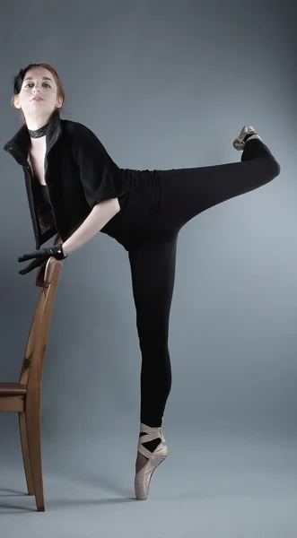Jovem bailarina realiza exercícios perto da cadeira — Fotografia de Stock