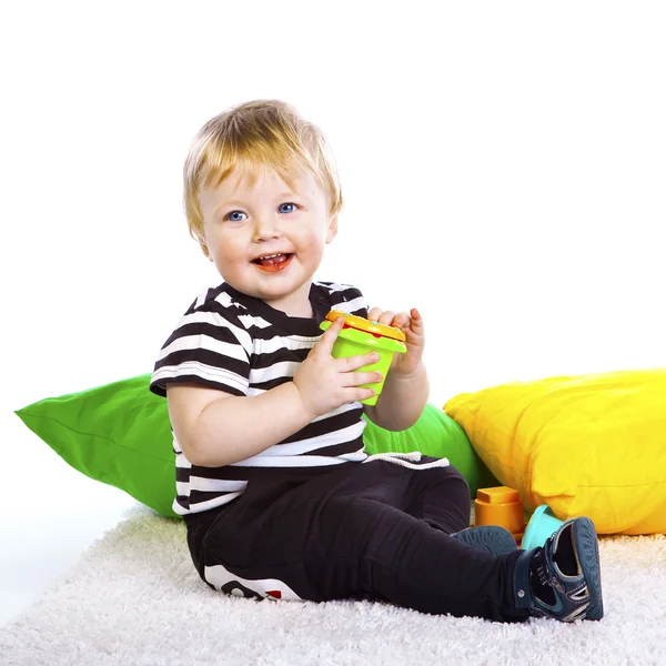 Um menino com a camisa listrada senta-se — Fotografia de Stock