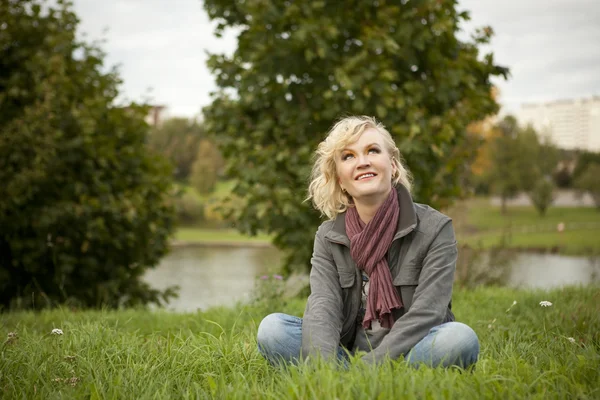 Blonde sits on the grass — Stock Photo, Image