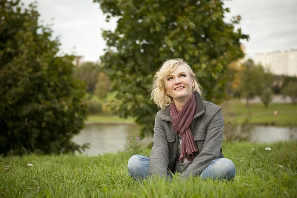 Blondynka siedzi na trawie — Zdjęcie stockowe