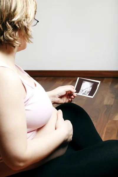 Femeie gravidă care se uită la imaginea cu ultrasunete — Fotografie, imagine de stoc