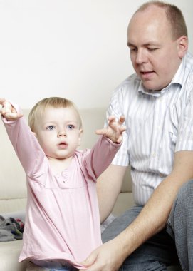 Father helping his baby daughter dress clipart