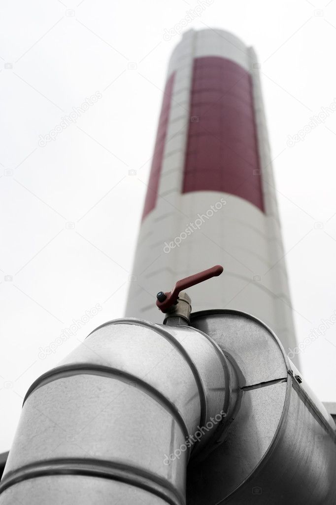 Industrial ventilation duct with a chimney in the background