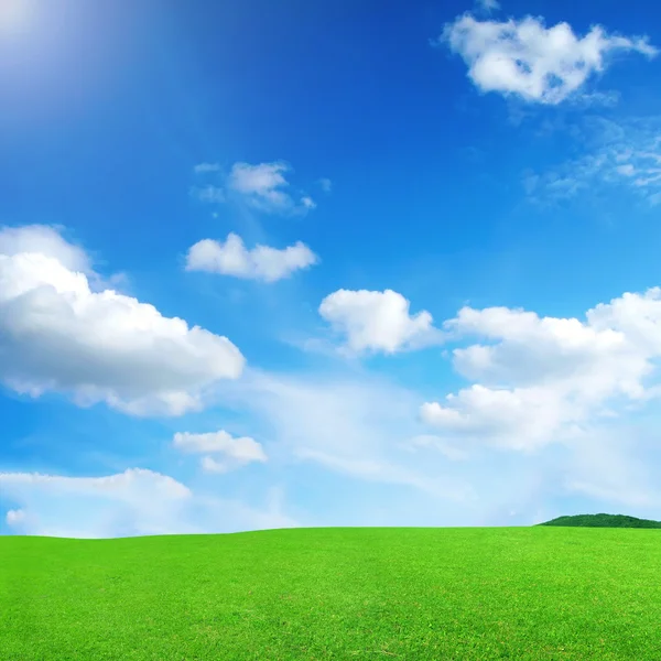 Голубое небо с облаками и зеленым лугом — стоковое фото