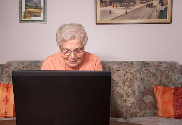 老妇人用一台笔记本电脑 图库图片