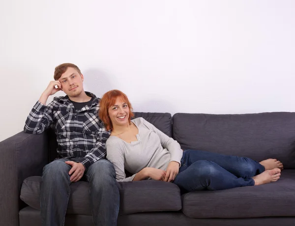 Una joven pareja en un sofá — Foto de Stock