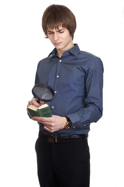 Joven Empresario busca en un pequeño libro con lupa. aislado en w — Foto de Stock