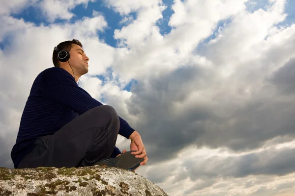 Молодой человек слушает музыку на вершине горы — стоковое фото