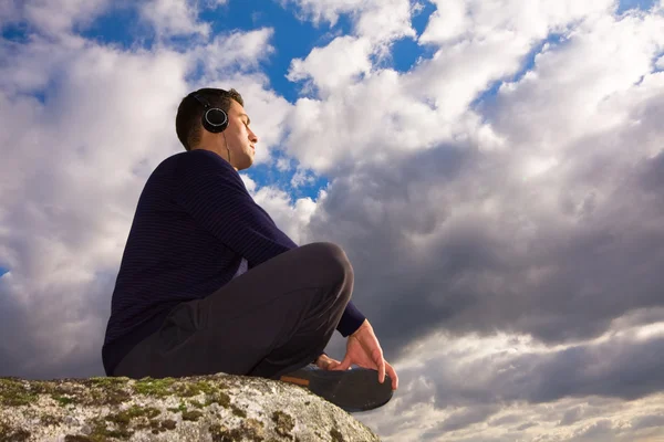 Jonge man luisteren muziek in de top van een berg — Stockfoto