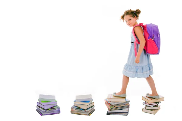 Portrait of girl with backpack walking from top to top of book p — Stock Photo, Image