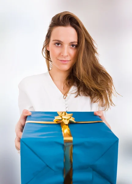 Όμορφη νεαρή γυναίκα με ένα δώρο που στέκεται στο εσωτερικό εμπορικά — Φωτογραφία Αρχείου