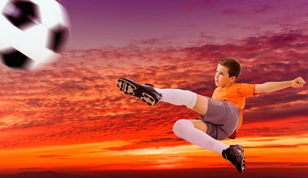 Soccer player doing flying kick with ball against a dramatic sk — Stock Photo, Image
