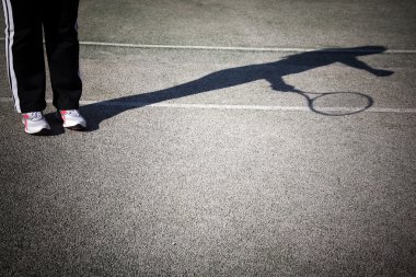 Shadow of a tennis player in action on a tennis court clipart