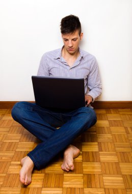 hom dizüstü bilgisayar üzerinde çalışan yerde oturan genç adam