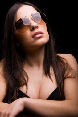 koyu arka plan üzerinde güneş gözlüklü seksi bir kadın portresi