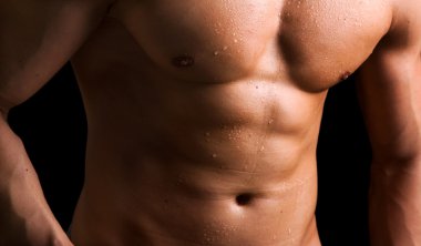 Muscled naked torso on black background clipart