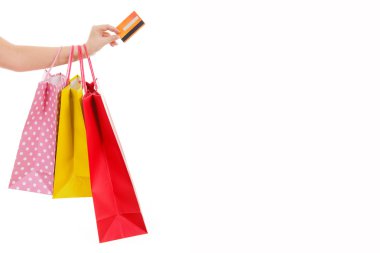 Female hand holding shopping bags and credit card, isolated on w clipart