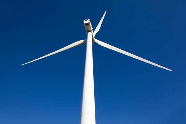 Vit vindkraftverk genererar el på blå himmel — Stockfoto