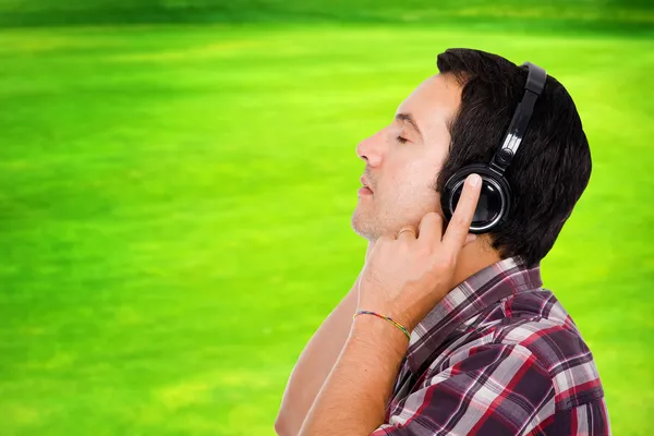 Schöner junger Mann hört Musik im Park — Stockfoto