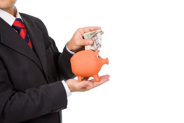 Business man inserting money into a piggy moneybox. Many space t — Stock Photo, Image