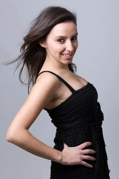 Güzel bir genç kadın gülümseyerek, gri bir arka planı — Stok fotoğraf