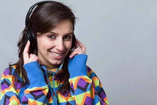Улыбающаяся молодая женщина слушает музыку в наушниках над синим баком — стоковое фото