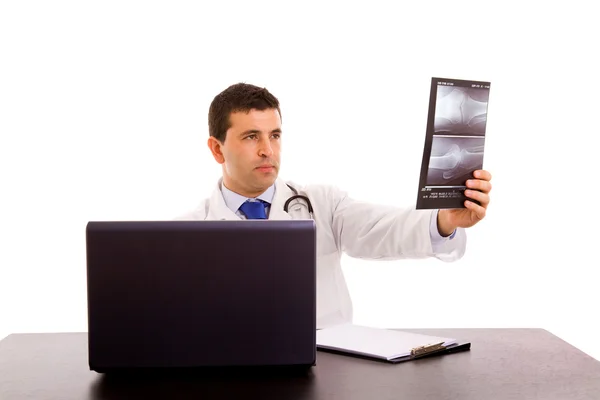 Молодой доктор смотрит на рентген, изолированный на белом — стоковое фото
