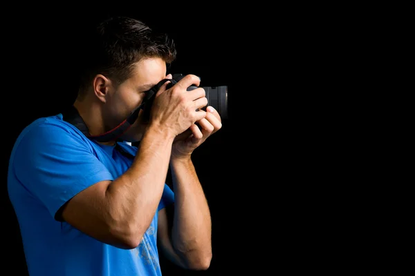 Молодой фотограф с камерой на черном фоне — стоковое фото
