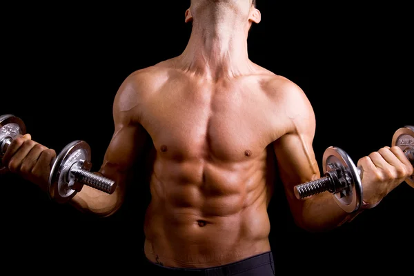 Musculoso joven levantando pesas sobre fondo negro . —  Fotos de Stock
