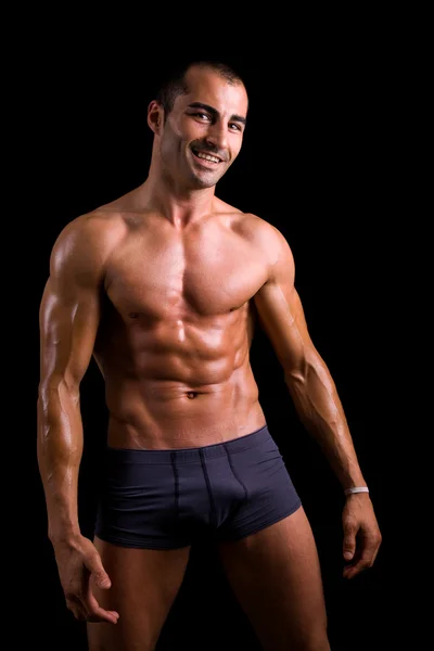 Ler muskulös ung man poserar mot svart bakgrund — Stockfoto