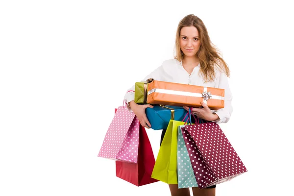 Beautiful young woman carrying shopping bags and gifts on white — Stock Photo, Image