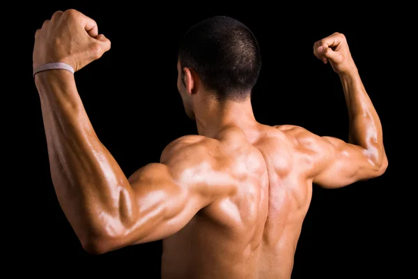 Porträt eines kräftigen Rückens eines jungen, muskulösen Mannes gegen dunkles B — Stockfoto