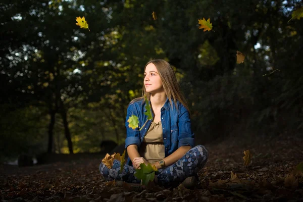 Красивая молодая девушка с опавшими листьями в осеннем парке — стоковое фото