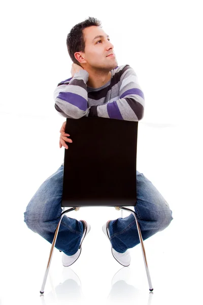 Nadenkend casual jongeman op een stoel, geïsoleerd op wit — Stockfoto
