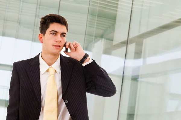 Ein hübscher junger Geschäftsmann telefoniert vor dem Büro. — Stockfoto