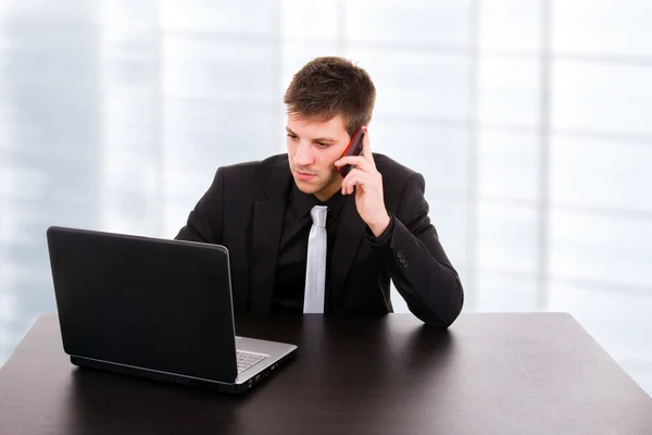 Giovane uomo d'affari che parla al telefono e lavora su è laptop — Foto Stock