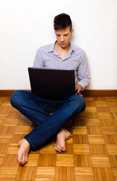 Hombre joven casual usando ordenador portátil en casa — Foto de Stock