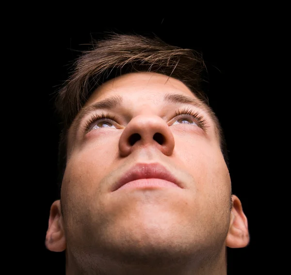 Junger Mann schaut nach oben auf schwarzem Hintergrund — Stockfoto