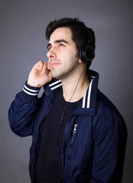 Handsome young guy listening to music in headphones — Stock Photo, Image
